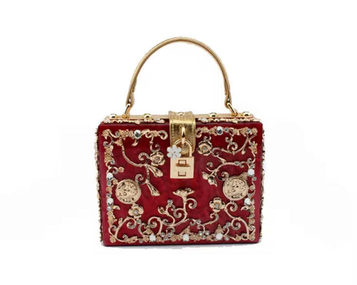 Decorative red handbag with gold embellishments on a white background
