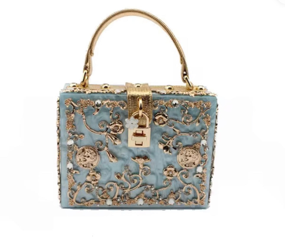 Decorative handbag with intricate gold patterns on a white background